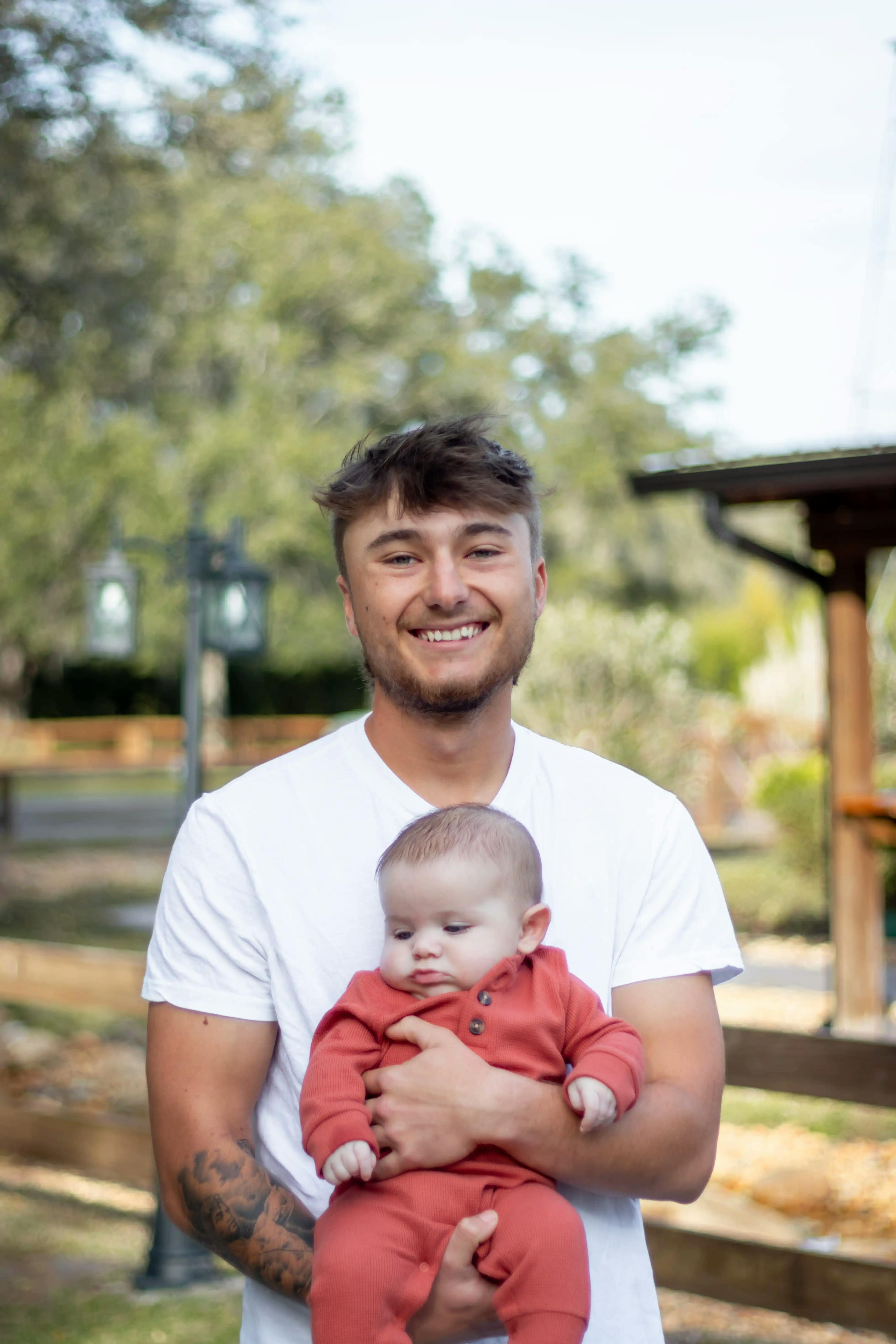 Young dad holding his three month old baby boy in rural setting