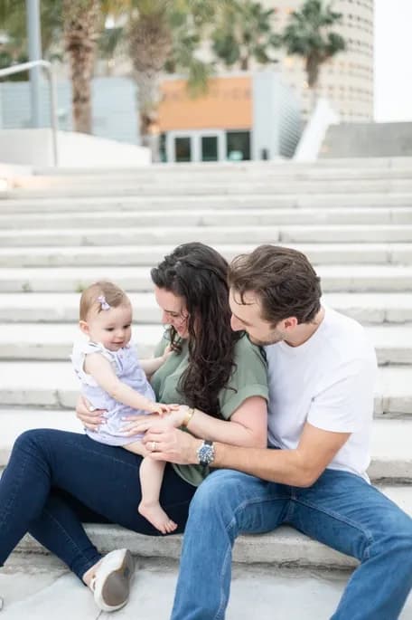 family photo of dad and mom smiling at their young daughters on steps in florida