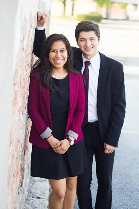 Young couple portrait dressed in business attire with a urban brick wall background
