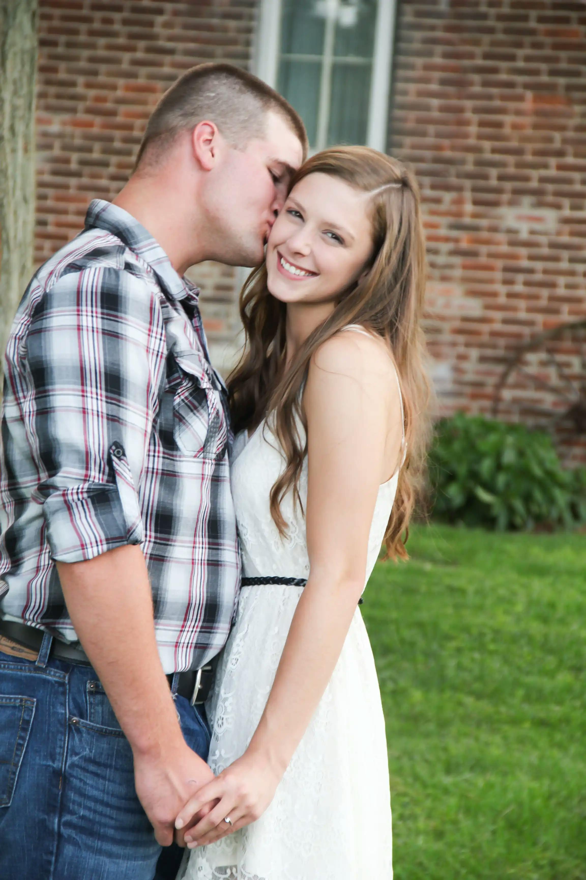 Guy kissing girls cheek in engagement photo